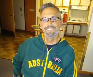 Ted is a tan, white male in his mid-40s with graying brown hair and matching beard; he is wearing dark-rimmed glasses and a forest-green hooded sweatshirt that says Australia